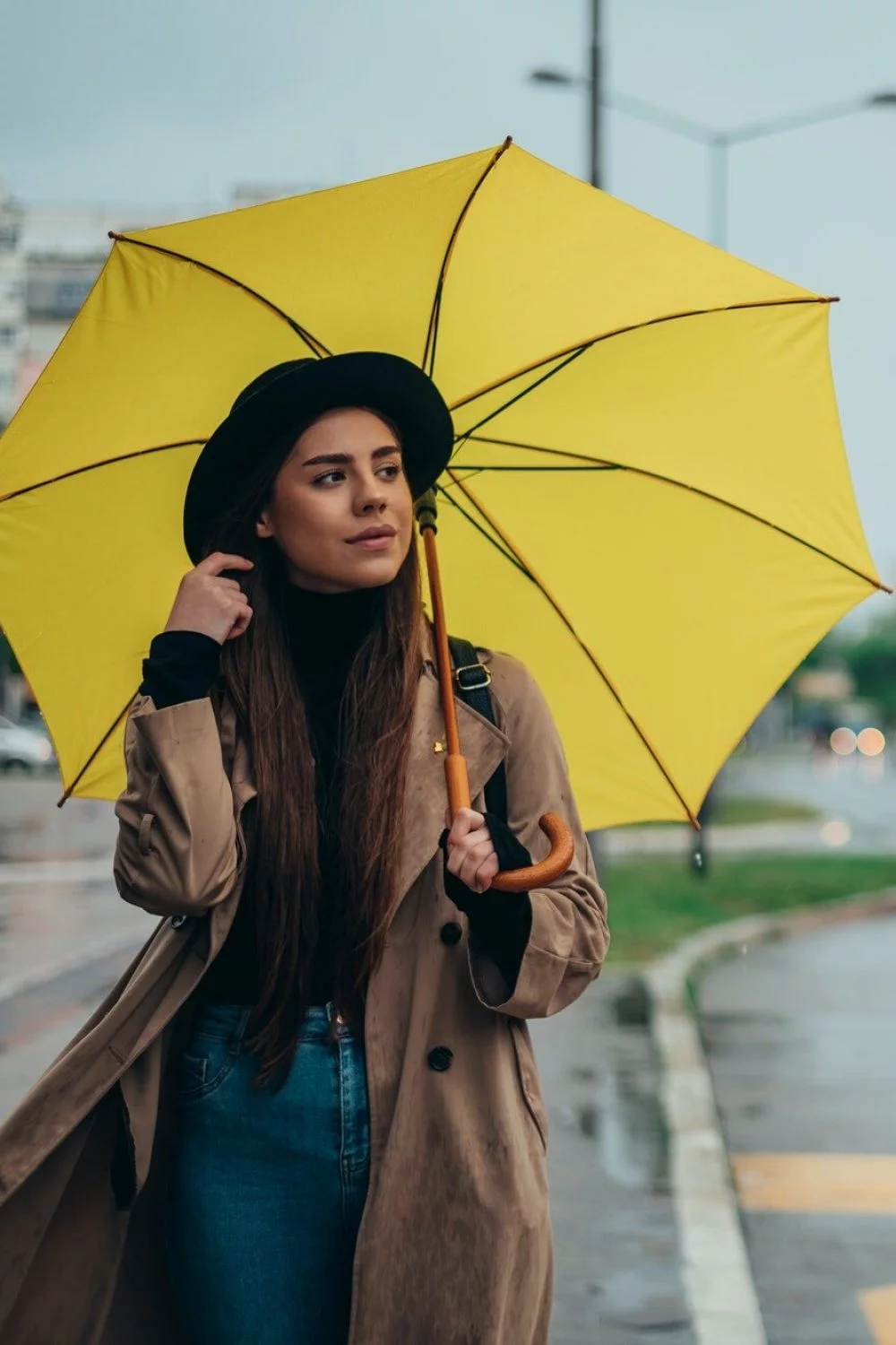 Young beautiful woman using a smartphone and holding a yellow umbrella